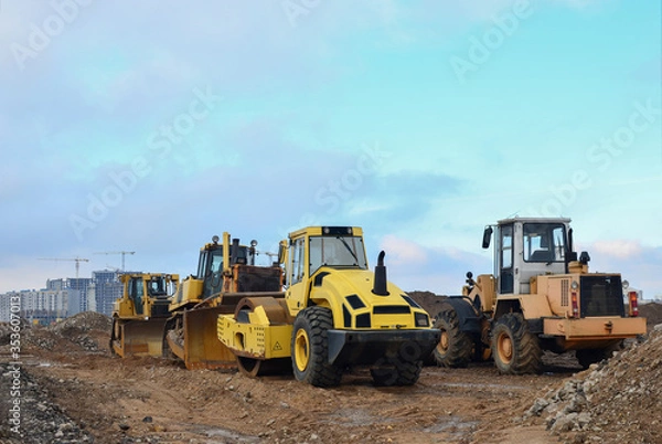 Fototapeta Soil Compactor, bulldozer and wheel loader during the construction of road at construction site. Heavy machinery for leveling the ground, land clearing, grading, pool excavation, trenching