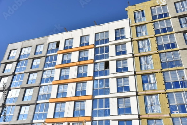 Fototapeta Construction of a new multi-storey building. Wall painting and insulation of the facade of the mineral wool.  Modern residential building. Housing renovation program