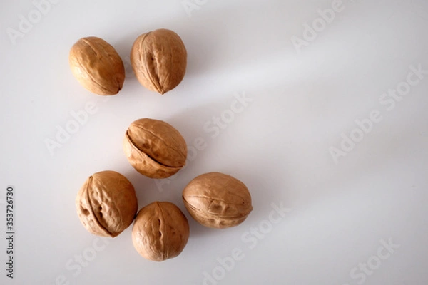 Fototapeta Walnuts spilled on a white table