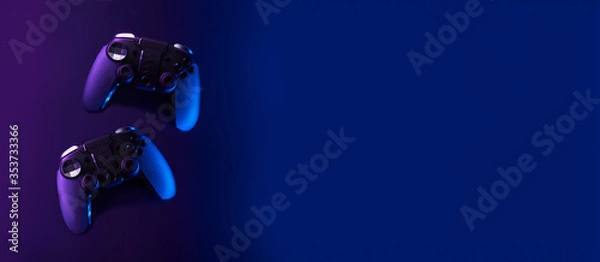 Fototapeta Black gamepads on black background in neon lights.