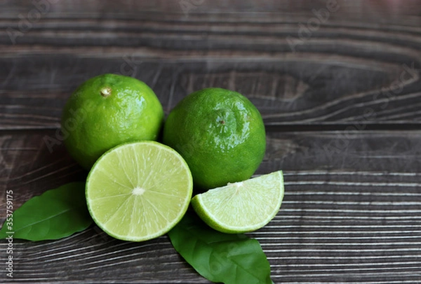 Obraz Natural fresh lime with green leaves on wooden background.