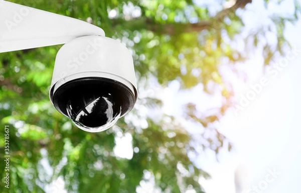 Fototapeta Modern public CCTV camera on a electric pole with blurred natural background. Intelligent reccording cameras for monitoring all day and night. Concept of surveillance and monitoring with copy space.