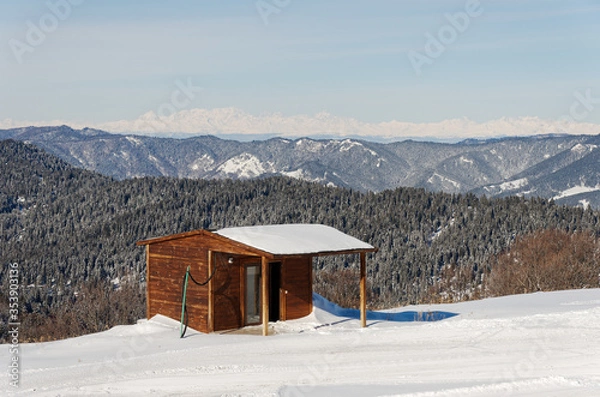 Obraz Wooden gatehouse on the mountain. A house on the edge of the ski slope. Winter view of the Caucasian ridge.