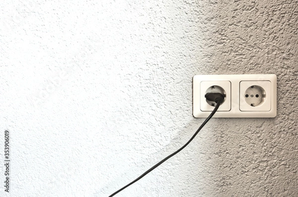 Fototapeta Double electrical power European socket with black cable and plug on white wall space for text