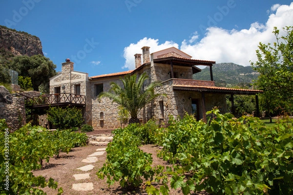 Fototapeta A wonderful stone house in green nature, Beautiful house view in the garden with blue sky and mountains.