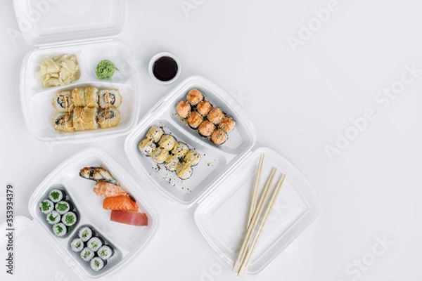 Obraz  Sushi and rolls set in a plastic box (top view). Delivery service consept.
