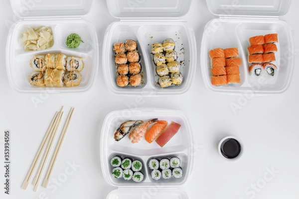 Obraz Assorted sushi and rolls mix in a plastic box (top view). Delivery service consept.