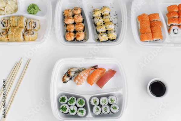 Obraz Assorted sushi and rolls mix in a plastic box (top view). Delivery service consept.