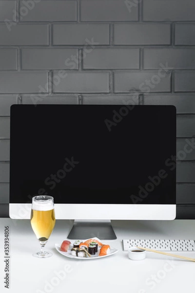 Obraz Assorted sushi and rolls near the computer. Eating at the workplace. Open copy space.