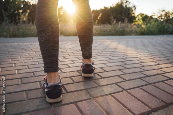 Fototapeta The girl runs from the side of the sunset on the path