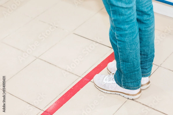 Fototapeta Person stand in line, legs close-up. Attention line on the floor of the store to maintain social distance. Concept of the coronavirus pandemic and prevention measures