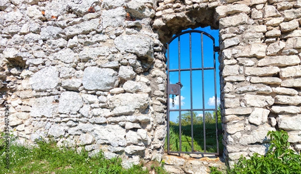 Fototapeta Stone castle wall with a metal passage to the courtyard