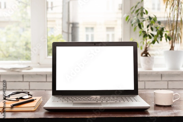 Fototapeta Laptop computer with white blank screen on work table. Work from home concept.