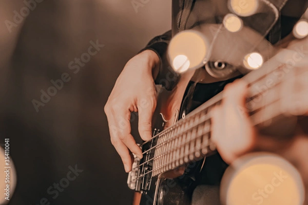 Obraz Man playing electric bass guitar blurred background with beautiful bokeh.