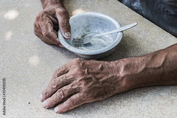 Fototapeta Hungry. Poor old man's hands an empty bowl. Selective focus. Poverty in retirement. Alms