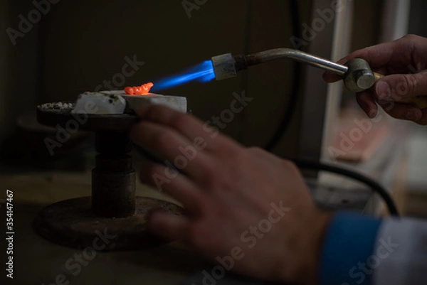 Fototapeta A dental technician makes partial dentures. The production of a false jaw or dental bridges using a manual gas burner. Close-up.
