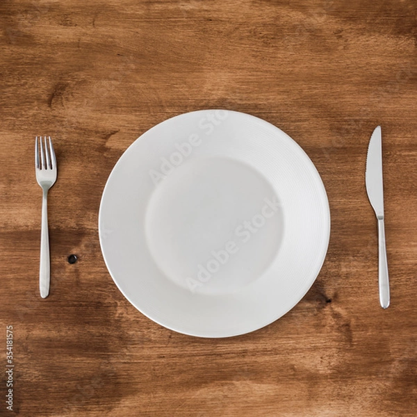Fototapeta empty plate with knife and fork on wooden background