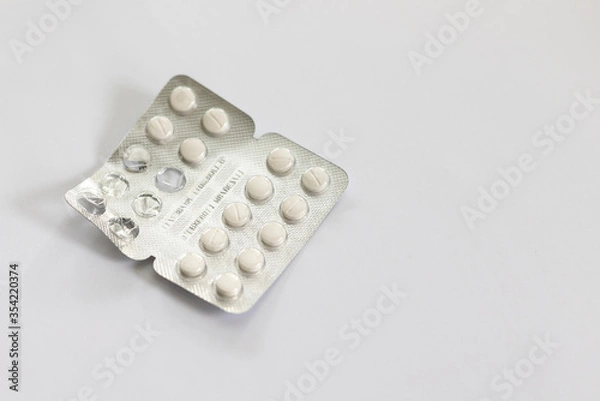 Obraz Foil packet of antihistamines with used pills. Small white pills on a white background