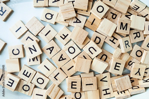 Fototapeta many identical wooden and square letters on a light background