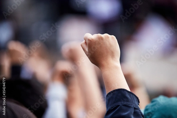 Fototapeta Hand in fist at a "black lives matter" rally in gathering, large group of protesters.