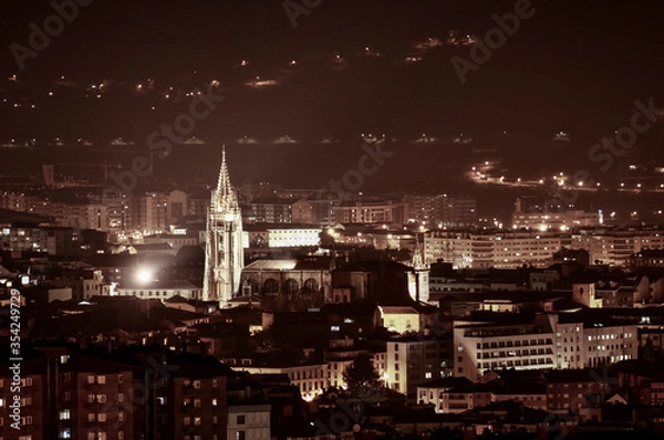 Fototapeta Night view of a cathedral surrounded by buildings in the middle of a city in northern of Spain