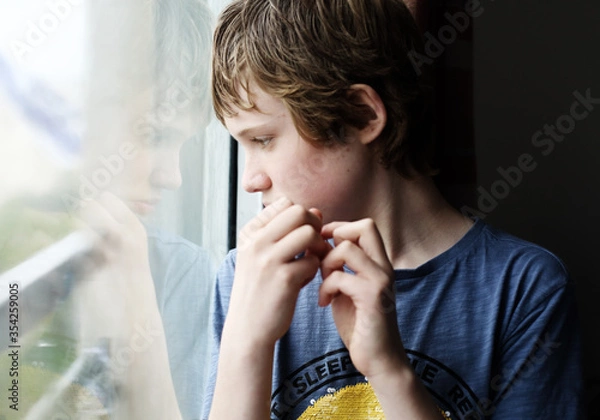 Obraz Cute 12 years old autistic boy looking through the window