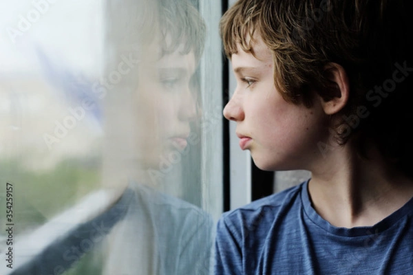 Obraz Cute 12 years old autistic boy looking through the window