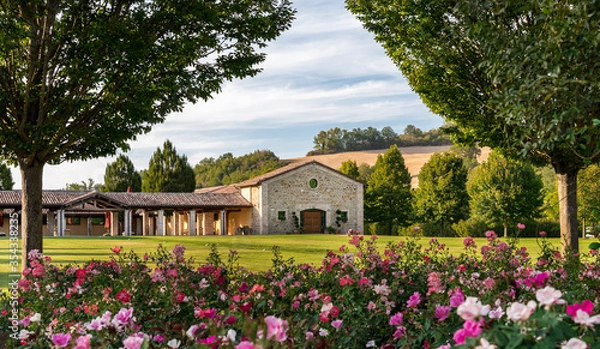 Fototapeta Tuscan village in the countryside, tourist site and relaxation, paved square with stones and grass, typical houses background