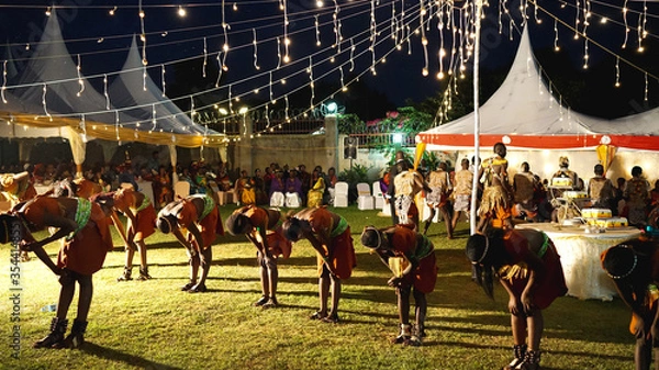 Fototapeta Kampala, Uganda - July 09, 2017: local performers in Uganda sing, dance and play traditional music at the wedding event, marriage ceremony in Kampala, culture and traditions in Uganda, local clothes