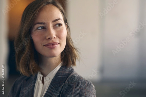 Fototapeta Close up portrait of beautiful business woman wearing a suit in office. Smiling and looking happy to the right. 