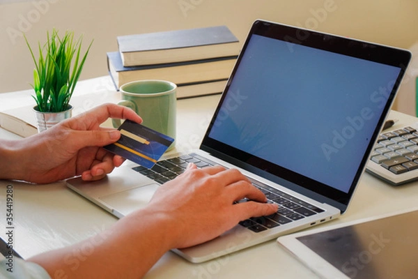 Obraz Hands holding credit card and using laptop. Online shopping