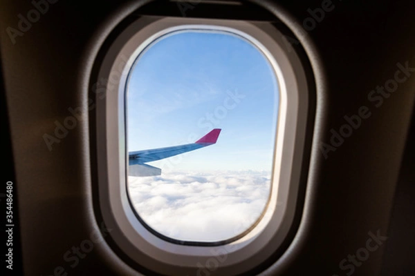Obraz Plane wing view from inside plane in midair with blue sky cloud background