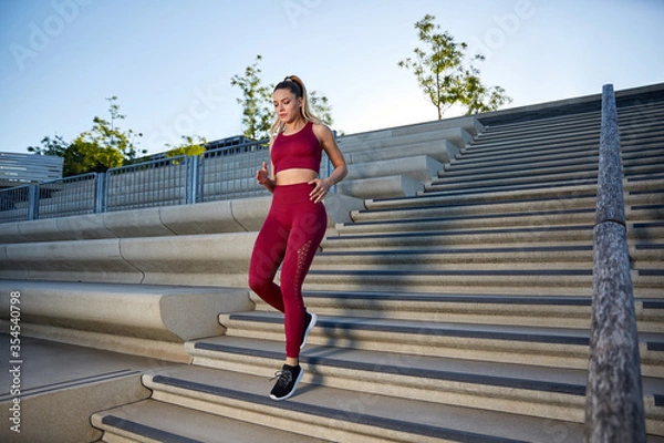 Obraz Outdoor jogging in the early morning in the city on a river, intensive running training on a staircase, High Intensity Interval Training, 