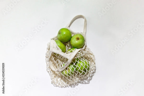Fototapeta Fresh apples in a string bag, eco-friendly product on a light  background. No plastic, only natural materials and natural products. Concept of life without plastic.