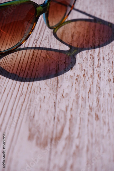 Obraz Sunglasses reflected  onto a wooden background