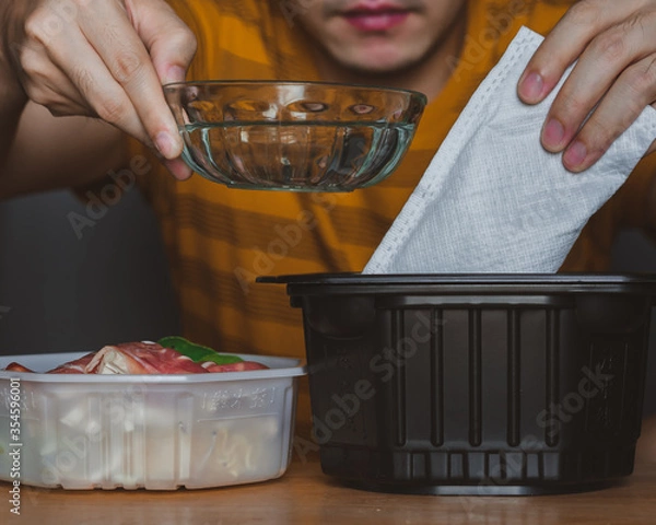 Obraz Man cooking self heating hot pot can order to home delivery ready to eat by heat from self heating pad which contains noodle,Sliced wagyu marbled beef,Cantonese vegetables,fried shrimp ball,mushroom.