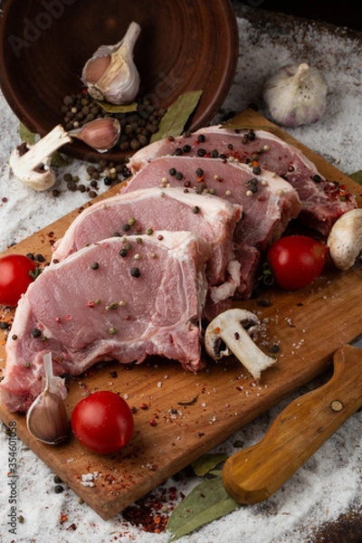 Fototapeta Meat, pork, steaks pork loin on a wooden background. Raw pork marinated meat isolated with vegetables. Advertising for meat shop and farm. Various kinds of meat and ready to cook concept. Top view.