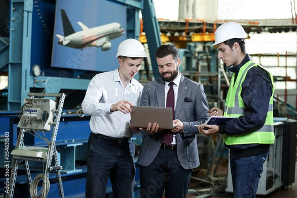 Fototapeta Portrait of a 3 men in a airplane manufactory. Two company managers and one factory worker deciding future plans. Business solution. 