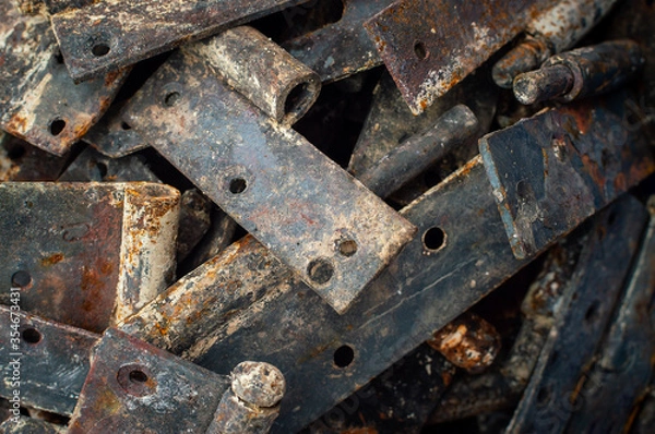 Fototapeta Background from heaps of old rusty metal door hinges. Selective focus. Raw materials for metal recycling
