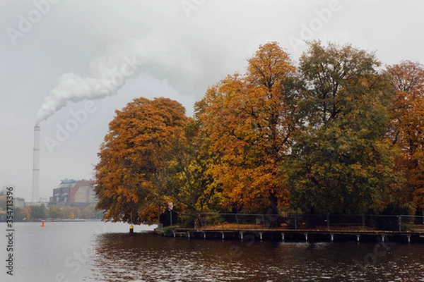 Obraz Glimpse of Spree river, near Treptower Park in Berlin, autumnal Chestnut Trees reflected in the water, in the background the smoke  from a factory chimney.