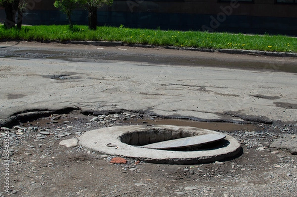 Fototapeta open well on a broken asphalt road