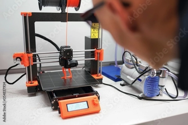Obraz Man checking 3d printer with display, process of making things on 3d printer in laboratory