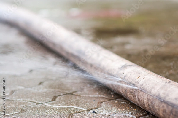 Obraz Leaky fire hose to extinguish fire, water is spilled, a ruptured hose.