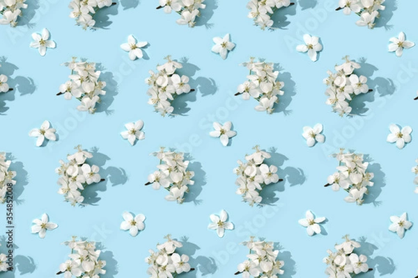 Fototapeta Apple tree floral pattern. Bright summer background. Spring white fruit flowers. Repeat spring texture. Creative trend composition. Many springtime elements. Blue