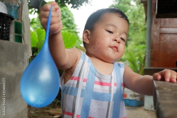Obraz An Asian boy is playing with a water balloon. Playing is learning.