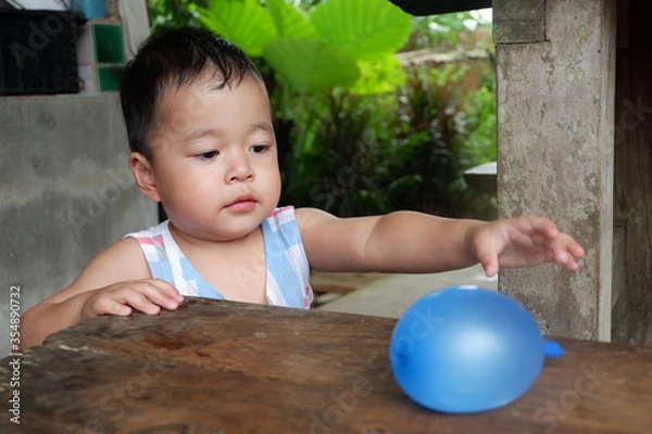 Obraz An Asian boy is playing with a water balloon. Playing is learning.