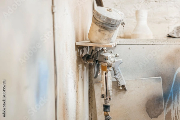 Fototapeta View of the paint shop of carpentry.  Three spray guns hang on the wall, close up view