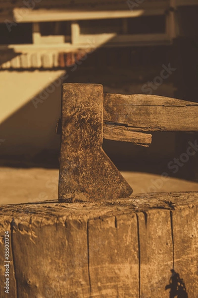 Fototapeta rusty ax stuck in a dry log on a sunny day