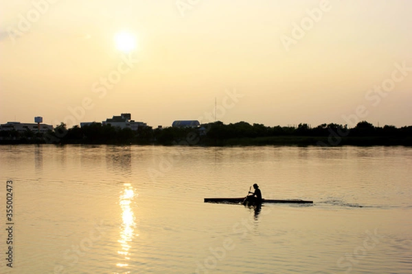 Obraz Man boating on the lake in sunset time