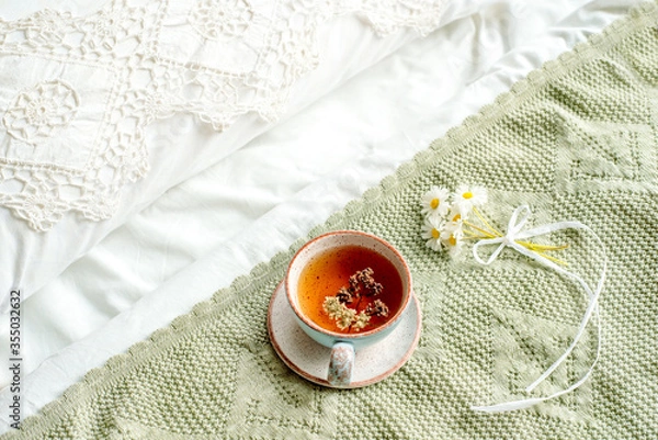 Fototapeta cup of natural herbal tea from mint and lemon balm in bed,morning close up. Cozy atmosphere.Diagonal lace,cotton white blanket,summer daisy flowers.breakfast.Provence and retro style